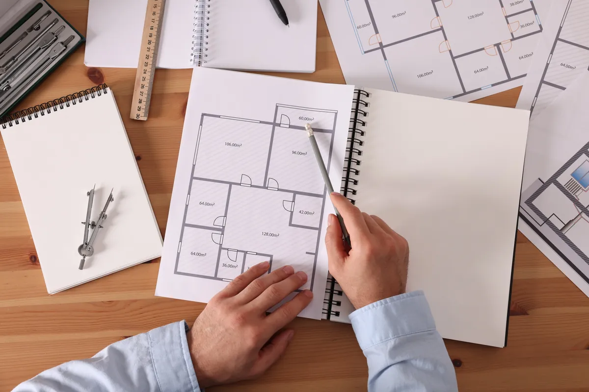Planos arquitectónicos y herramientas de dibujo sobre un escritorio